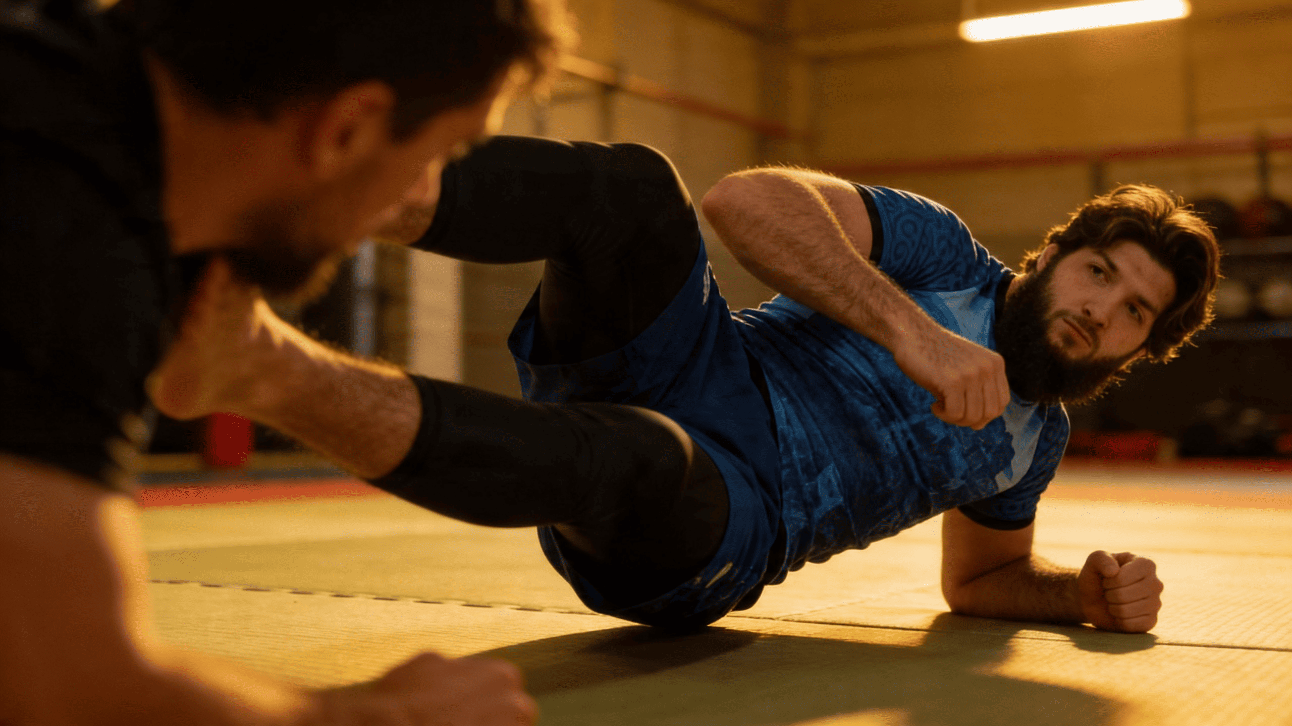 Pratiquant JJB en rashguard Hustle Fightwear pendant une session de grappling sur tatamis