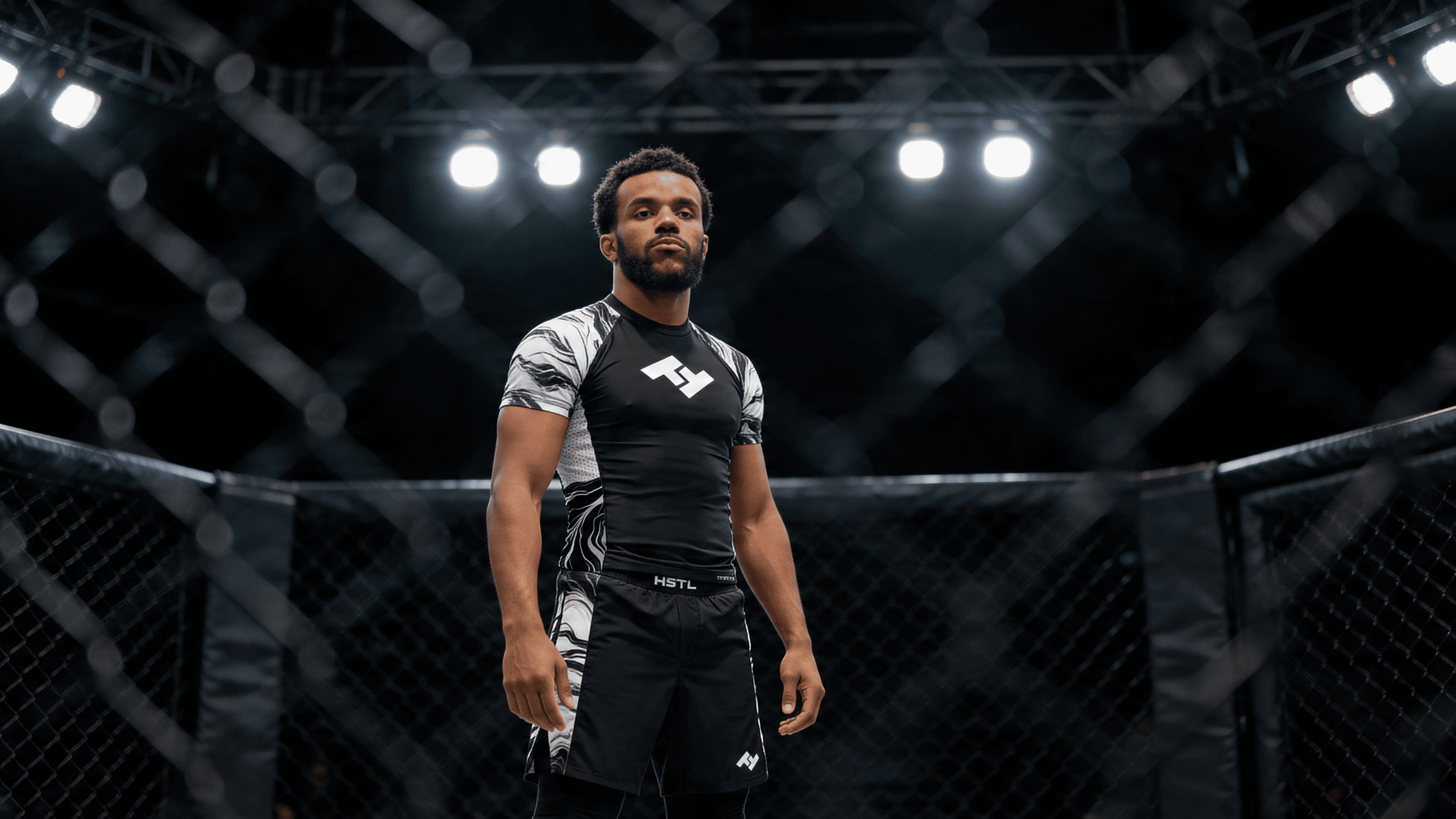 Combattant MMA portant un short Hustle Fightwear debout dans une cage MMA