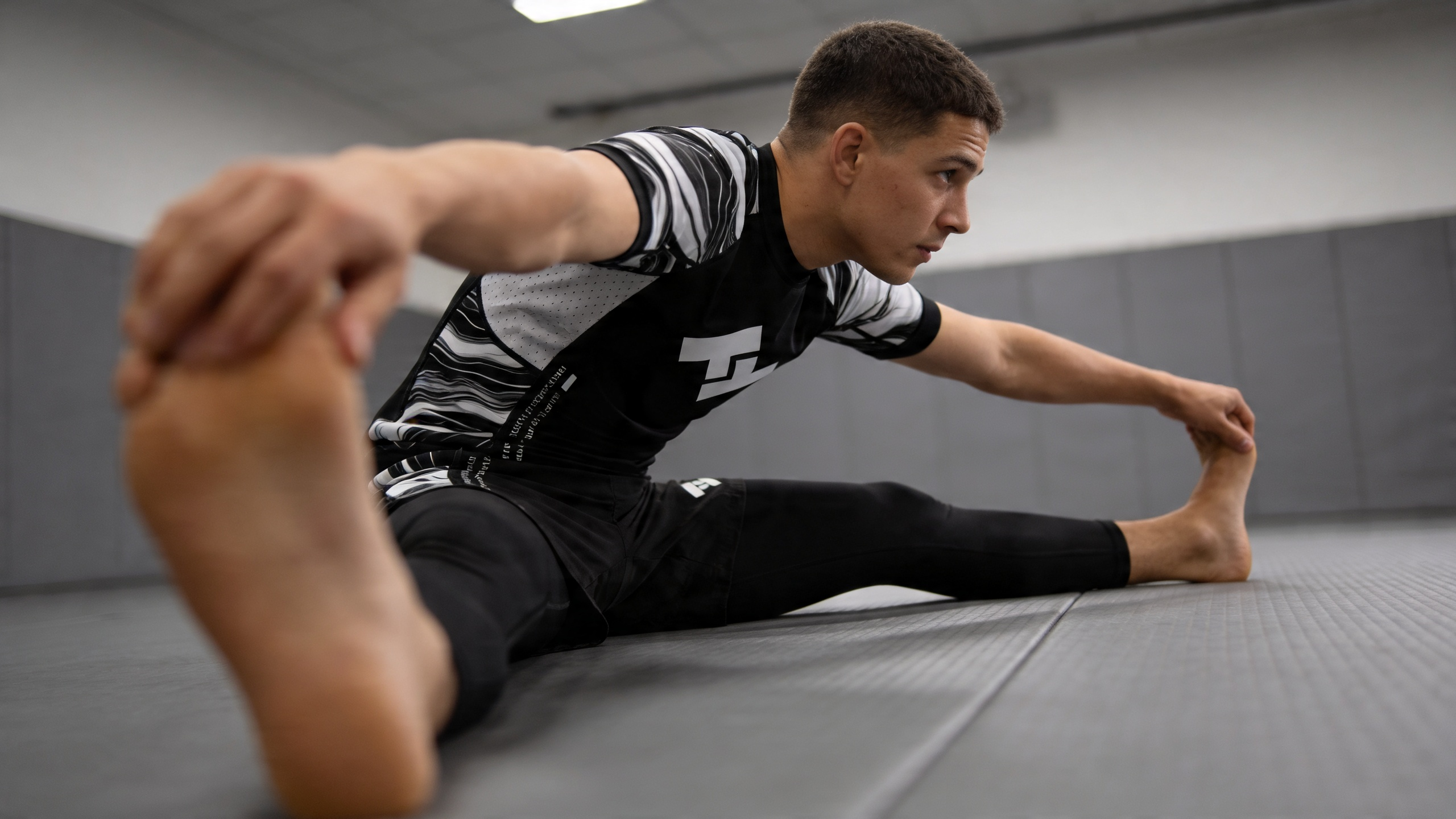 Grappeur portant un short Hustle Fightwear sur tatamis gris avant un entraînement