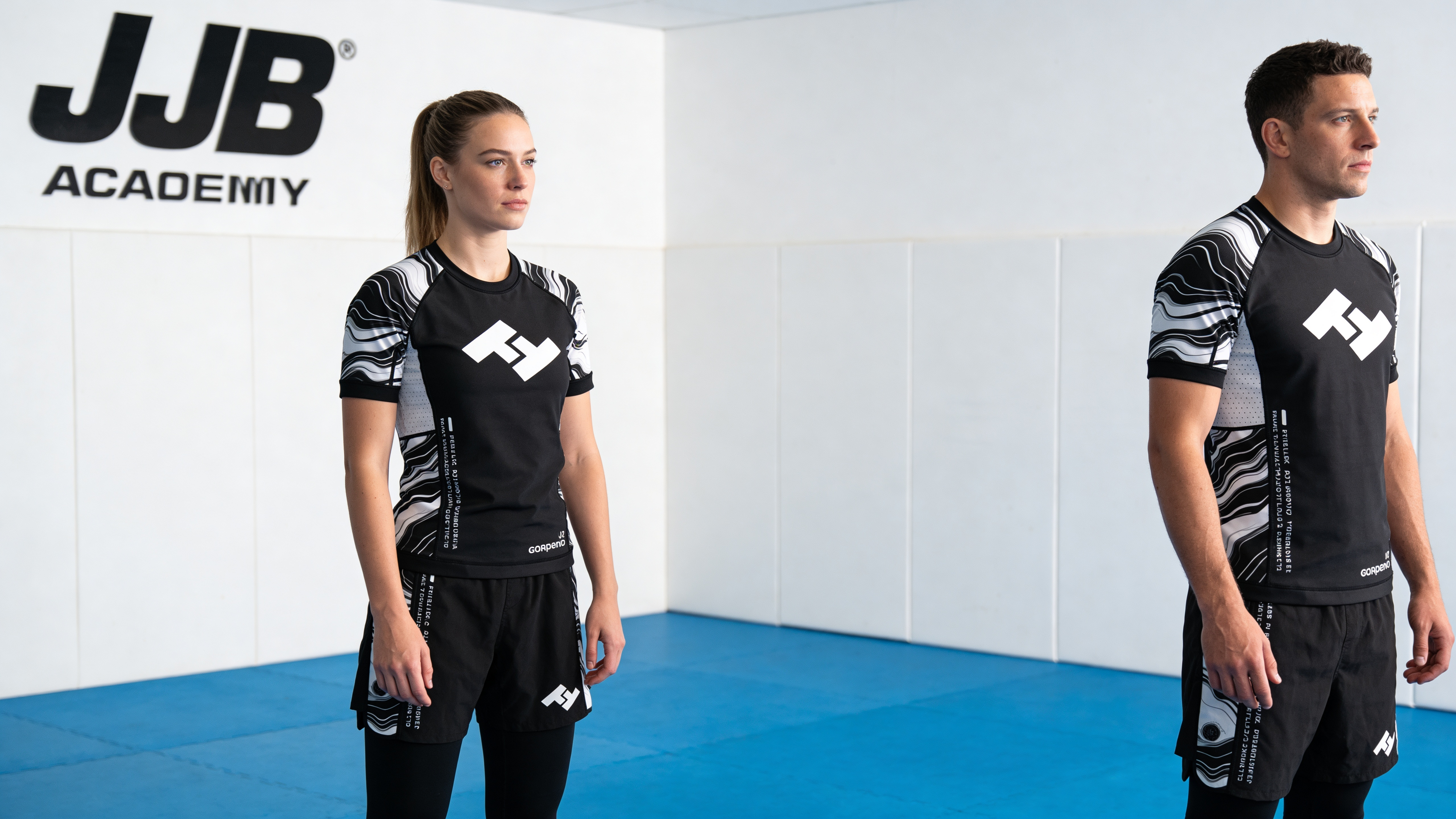 Rashguard homme et rashguard femme Hustle Fightwear portés côte à côte sur tatamis