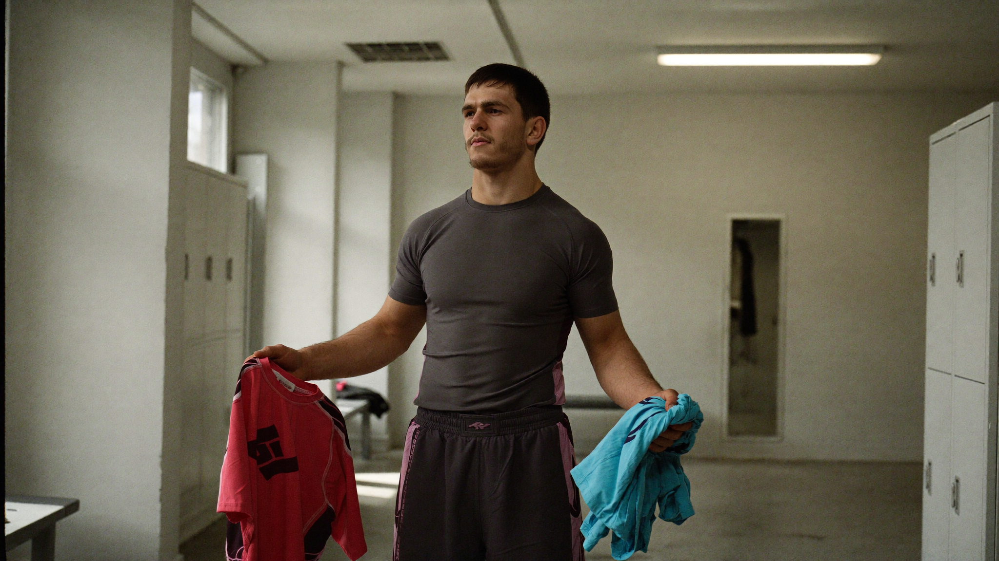 Grappler comparant deux rashguards de marques différentes dans un vestiaire de salle de JJB